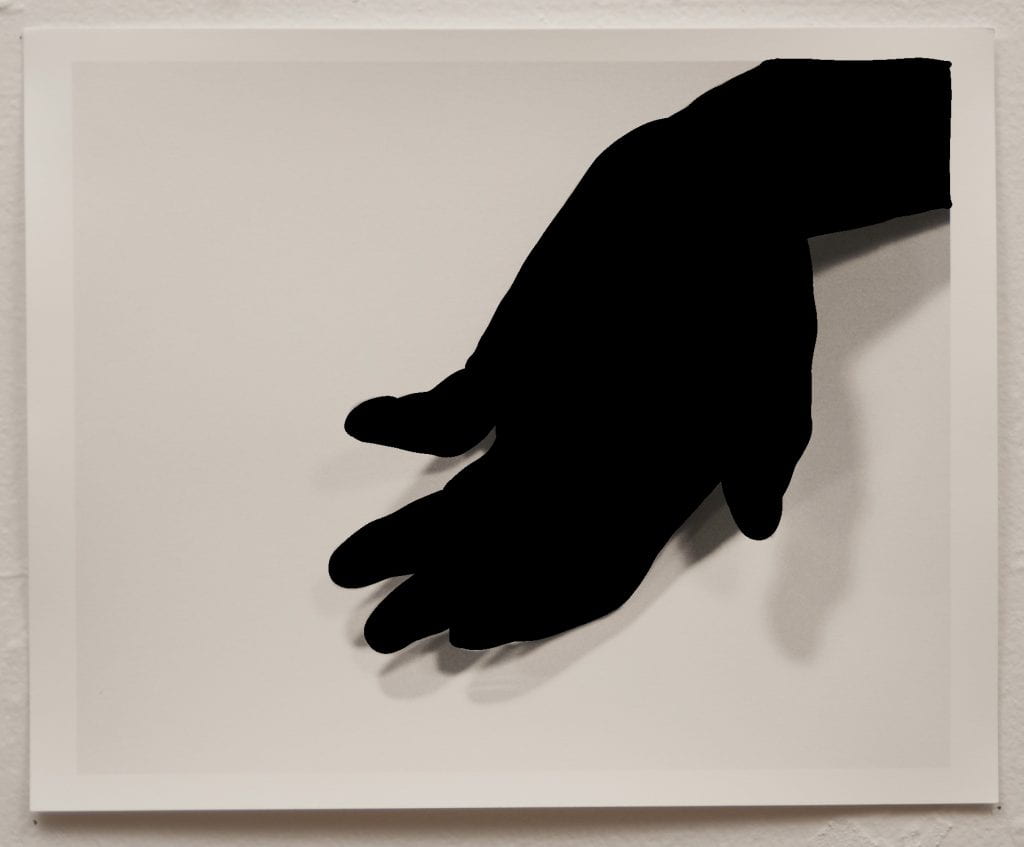 A black outline of a hand, palm facing up, on paper.